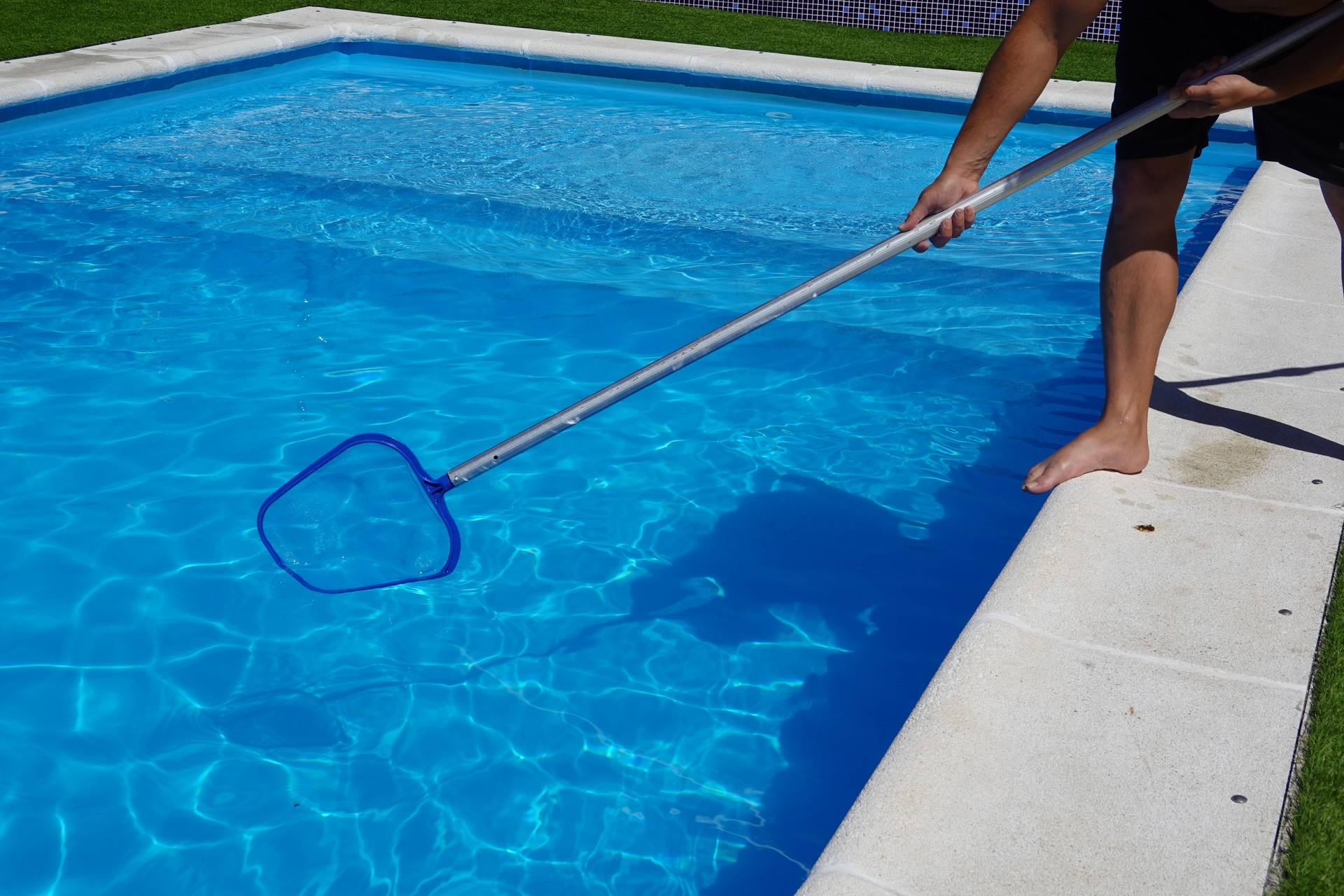 man cleaning the pool surface with pool cleaner mesh or skimmer